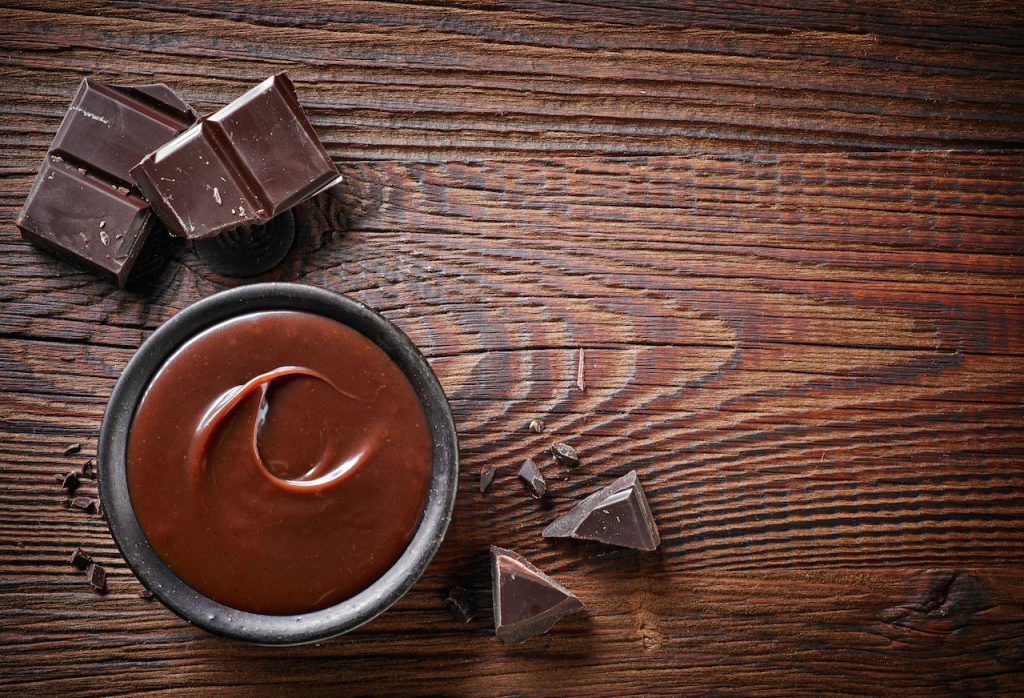 47855364 - chocolate cream and chocolate pieces on wooden table, top view
