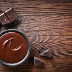 47855364 - chocolate cream and chocolate pieces on wooden table, top view